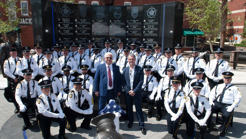 Lazar Finker and Eugene Frenkel stand with police officers in front of a police memorial wall in Jacksonville, Florida.